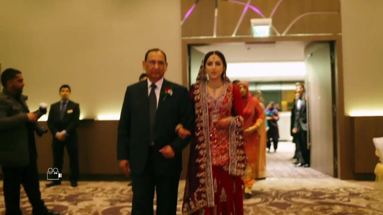 Destination wedding film still of Ayesha walking in with her father at her wedding in the United Kingdom