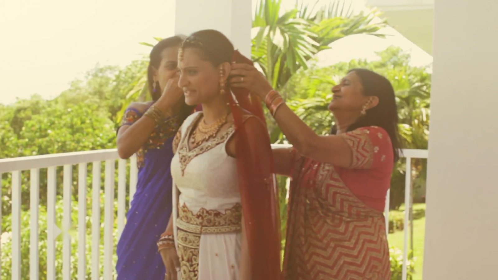 Luxury wedding in Jamaica: the bride being dressed by family on a balcony before the ceremony, from our Jamaica destination wedding film