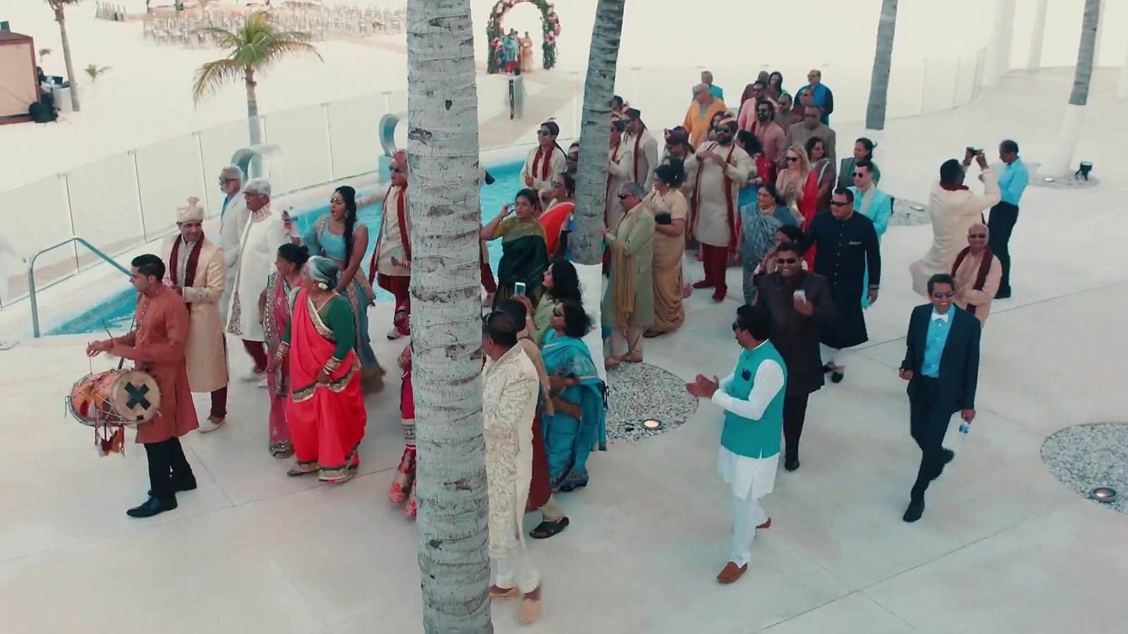 Mexico destination wedding film still: the wedding procession arriving through the resort grounds, from our destination wedding film in Mexico