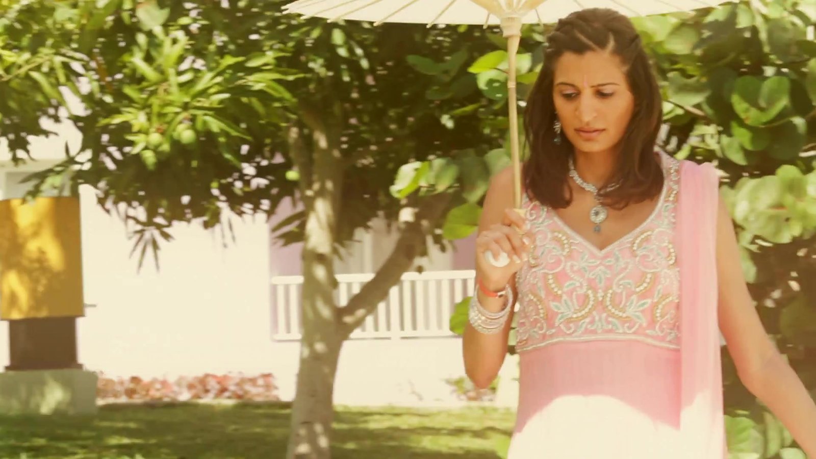 Portugal destination wedding film inspiration: a member of the wedding party holding a white parasol in a garden, from our destination wedding film in Jamaica
