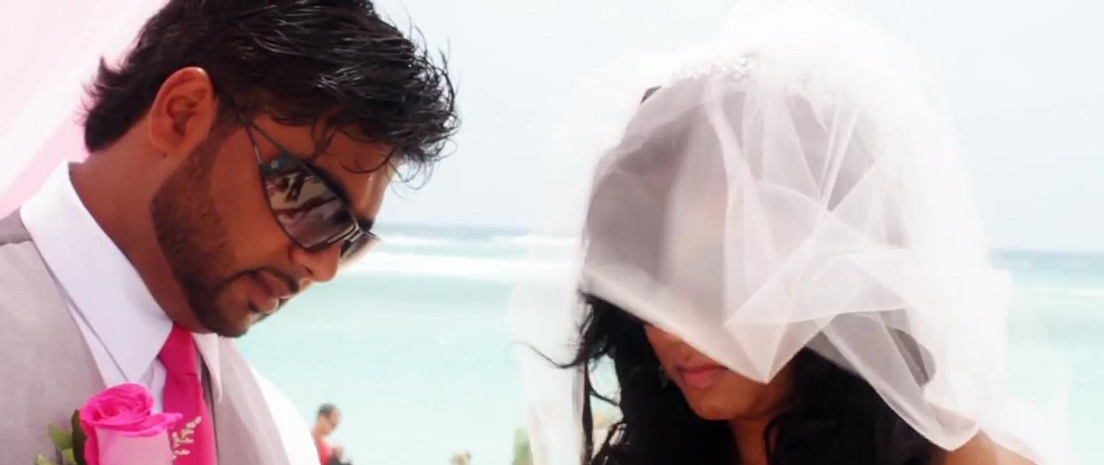 Punta Cana wedding videographer still: the groom beside his veiled bride at their beach ceremony, from our wedding film Fiona + Ricky