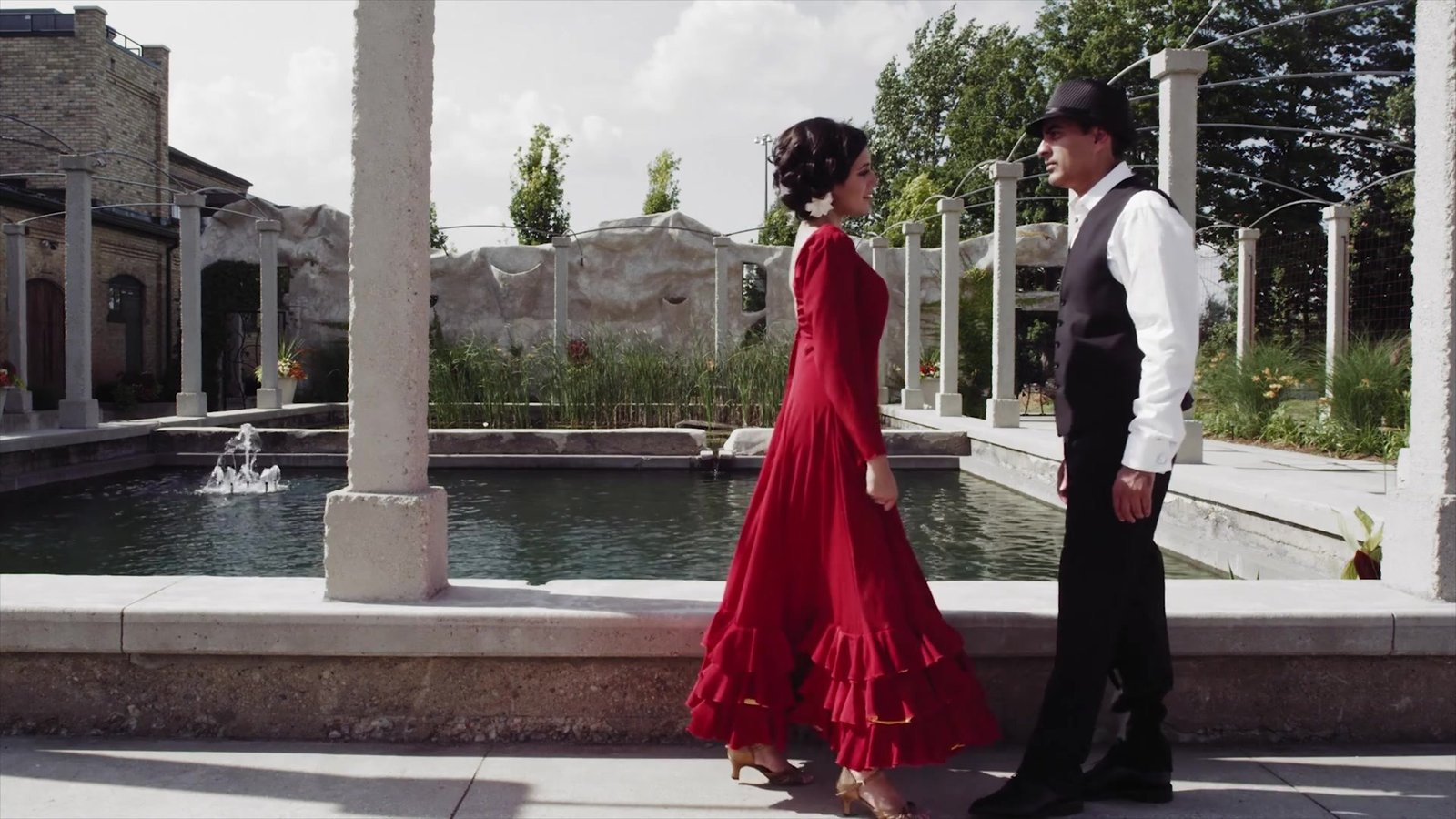 Luxury wedding in Spain inspiration: a couple meeting beside a fountain in a stone courtyard, from our concept film The Secret of Flamenco