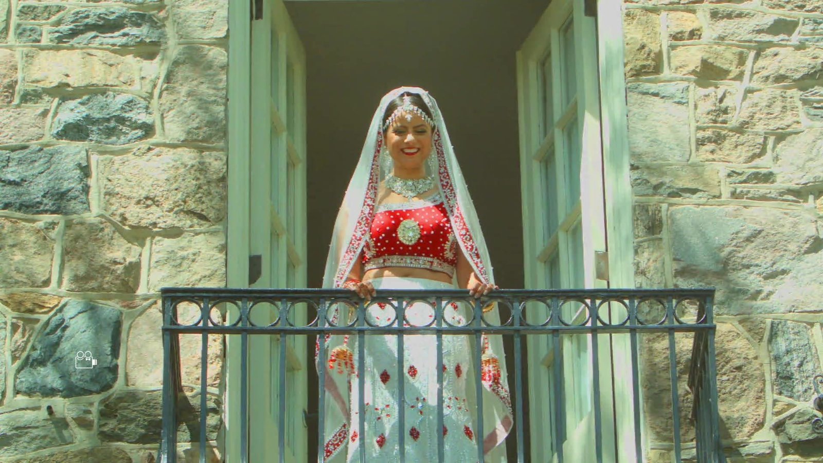 UK luxury wedding films guide: the bride standing on a balcony in Monica and Christian's wedding film
