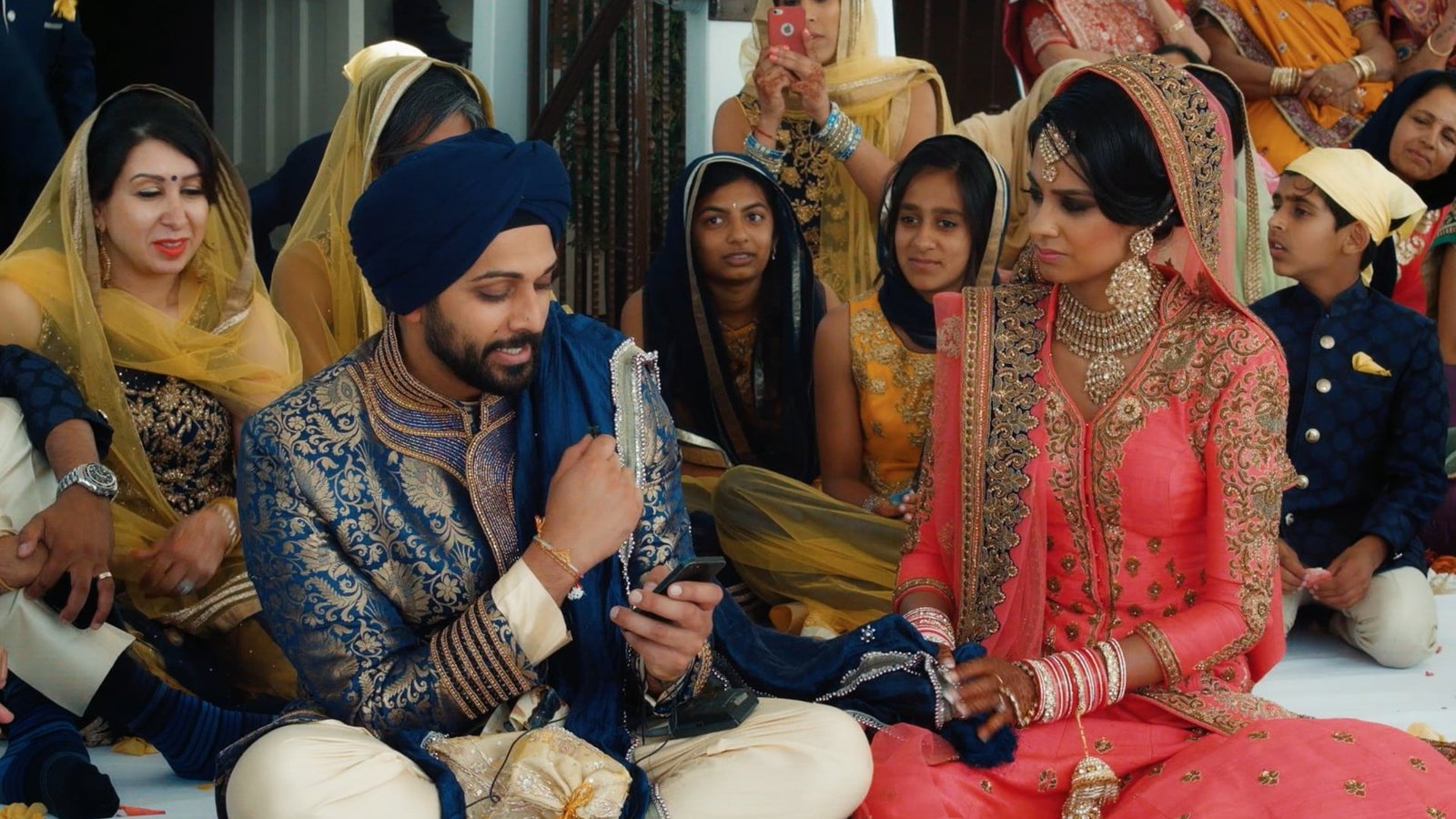 UK luxury wedding films guide: Simranjit and Amit seated with family during their wedding ceremony